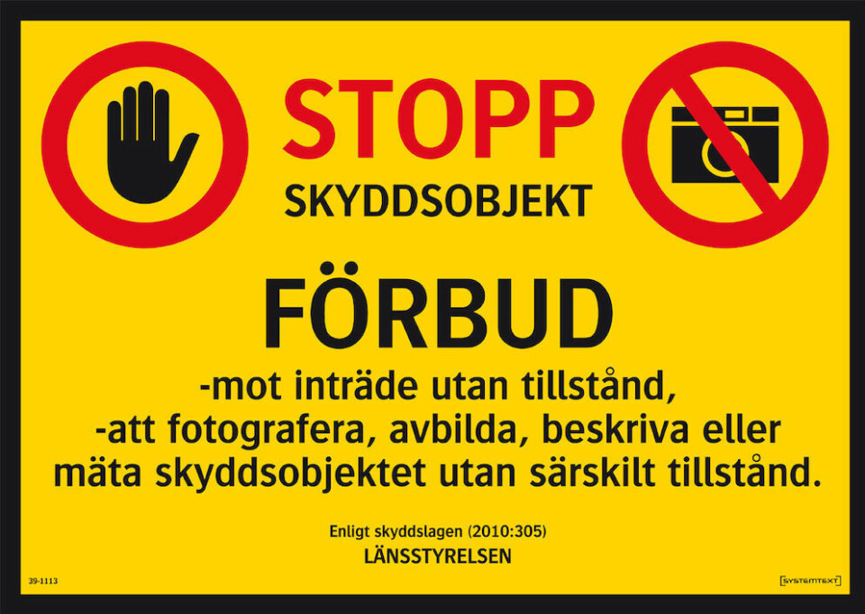 Så här kan en modern förbudsskylt mot fotografering av skyddsobjekt se ut. Notera den överkryssade kamerasymbolen uppe till höger på skylten som krävs för just fotoförbud.
