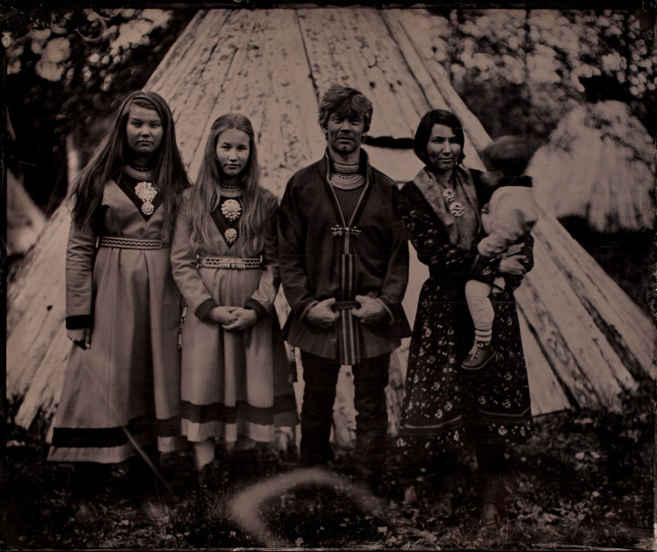 Familjen Åhren framför en träkåta.